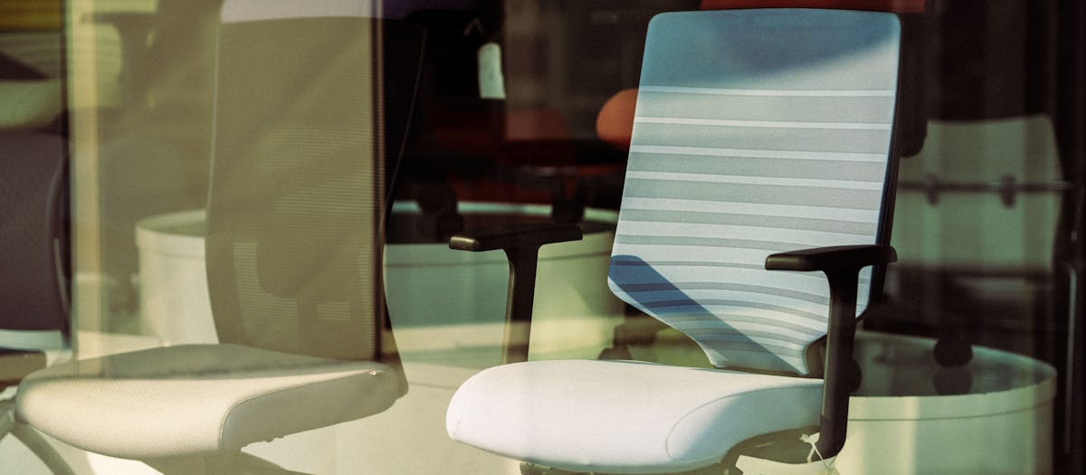 Contemporary office chairs displayed behind glass, offering modern ergonomic solutions for workspace.